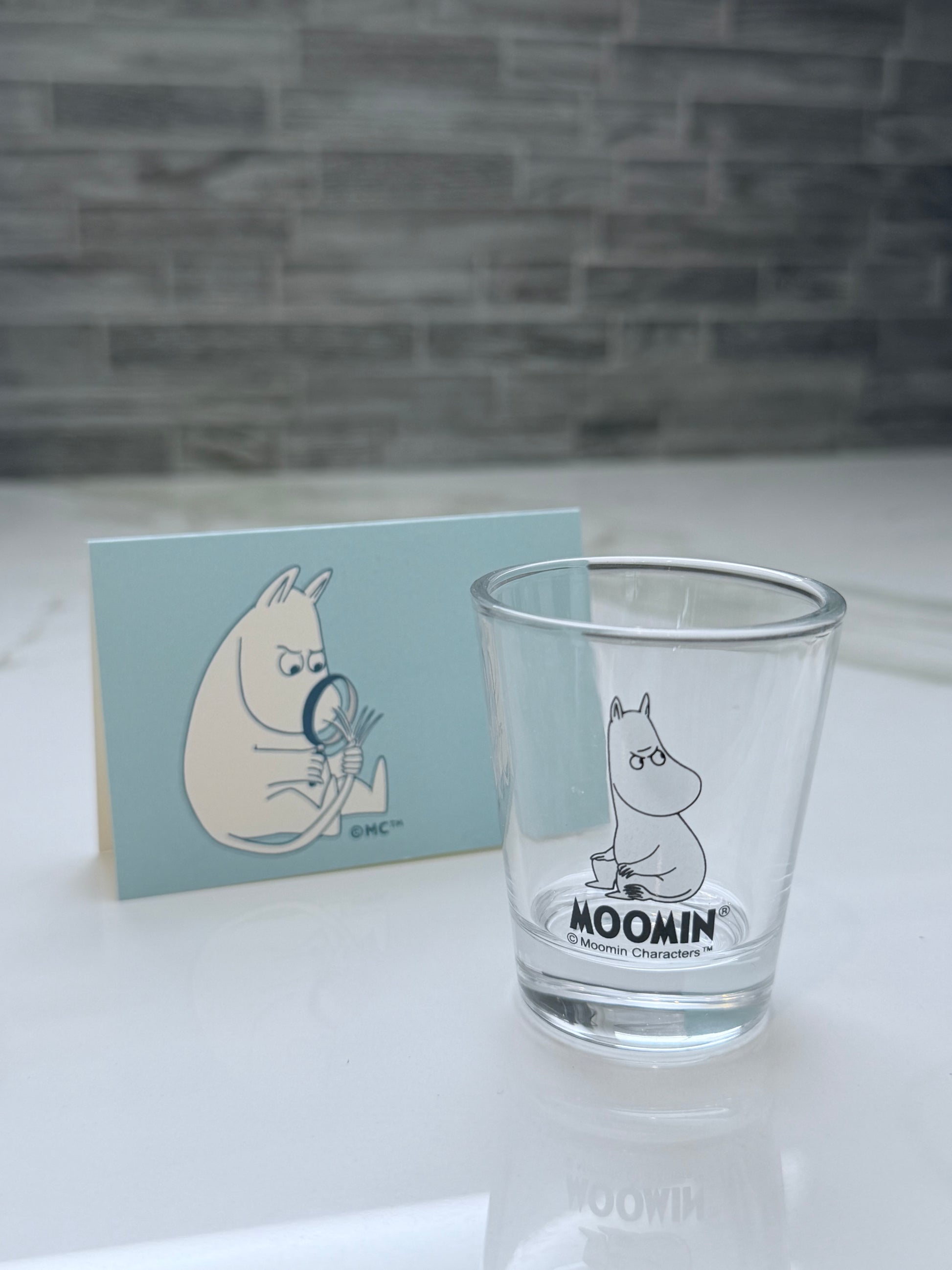 Clear glass with Moomin character design on a white surface